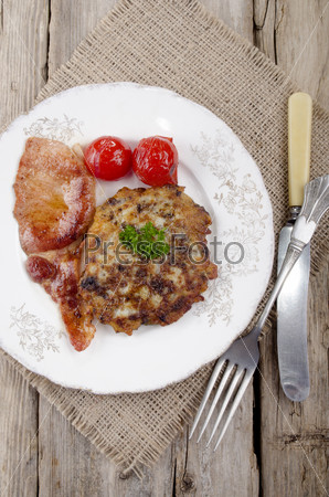 warm irish black pudding boxty with grilled bacon and cherry tomato on a plate