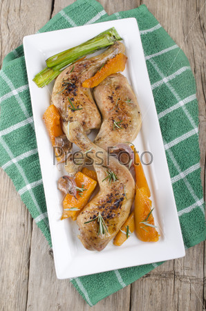grilled chicken legs with pumpkin, garlic, leek on a plate