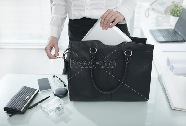 Женщина кладет планшет в сумку