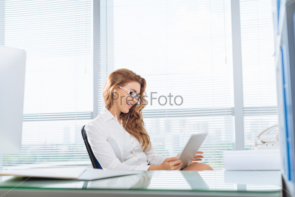 Businesswoman relaxing in office watching movies on tablet computer