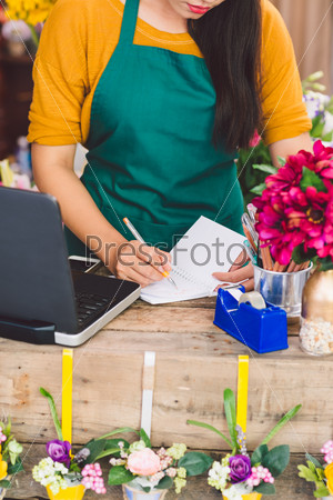 Worker at cash desk writing in notepad