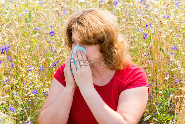 Fat woman with allergic rhinitis in meadow