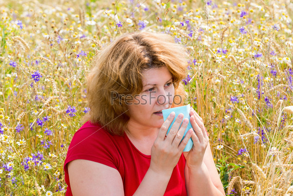 Fat woman with allergic rhinitis in meadow