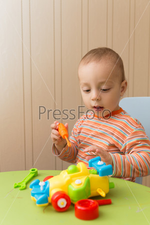 little boy repairs auto sitting at the table