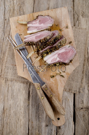 lamb fillet, meat fork and knife on wooden board