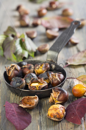 Roasted chestnuts in a pan on the old table.