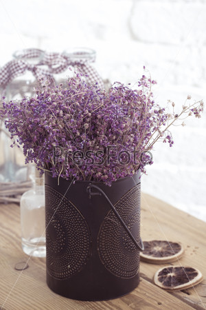Rustic home decor, provence style. Lavender bouquet of dried field flowers and glass spice jars on wooden bench.