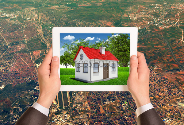 Hands holding tablet pc with image of house on the