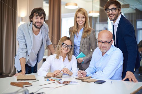 Company of successful business partners looking at camera in office
