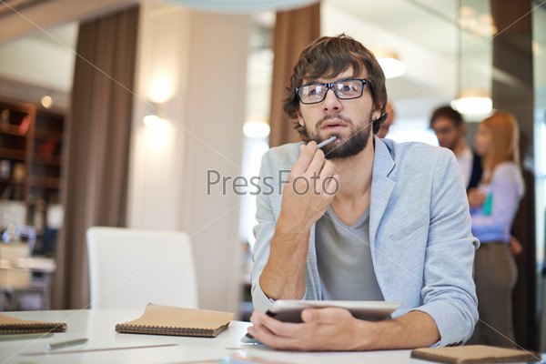 Handsome businessman in casual sitting at workplace on background of his partners