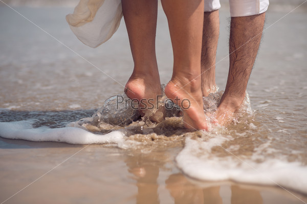 Feet of couple kissing on the beach