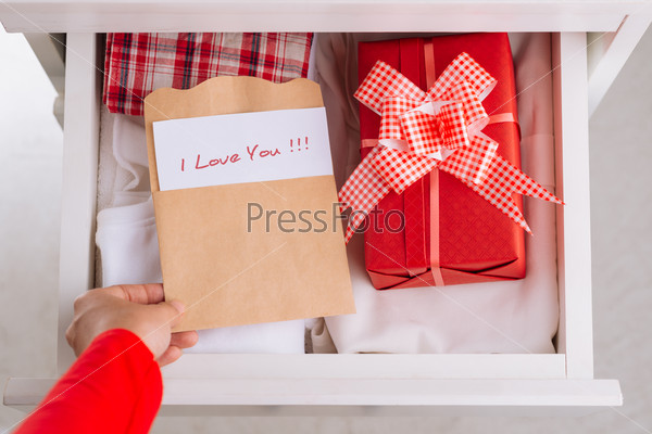 Close-up of girl putting card and a gift box in the drawer