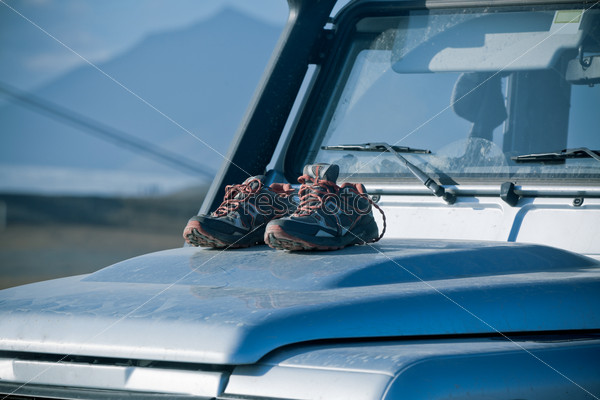 Trekking shoes are drying on a dirty 4wd car bonnet. Adventure mood