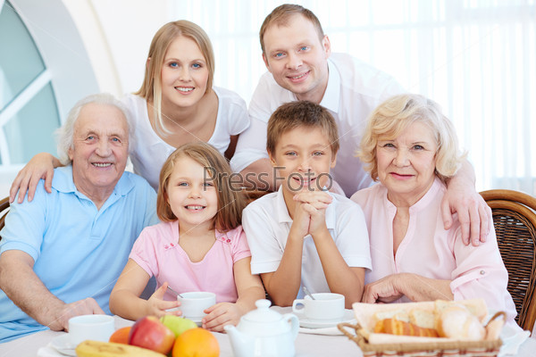 Portrait of happy senior and young couples and their children sitting by dinner table, stock photo