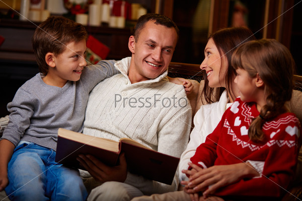 Portrait of happy family reading book on Christmas evening at home