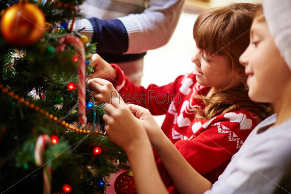 Happy kids decorating Christmas tree for holiday