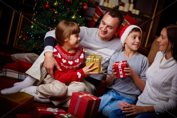 Portrait of friendly family with gifts spending Christmas evening at home