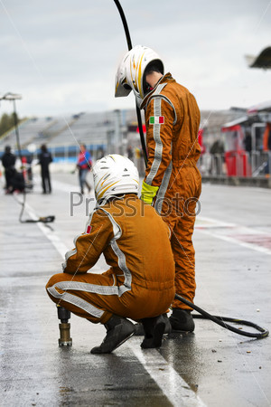 Pit Crew anticipating the arrival of their race car during a tyre change pitstop because of wet race conditions