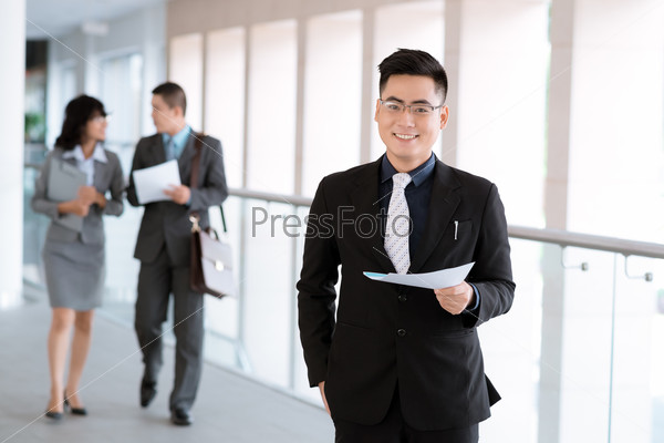 Portrait of successful manager on the background of his colleagues discussing a document
