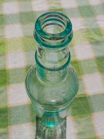 Green bottle on green tablecloth on table - selective focus on bottle top