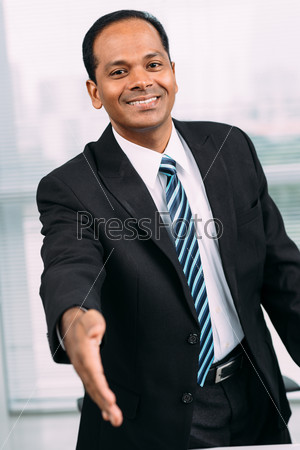 Smiling Indian businessman outstretching hand for a handshake