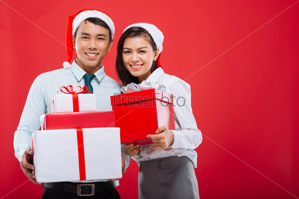 Happy young business people holding Christmas gifts and looking at the camera