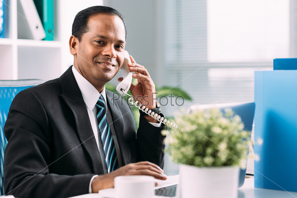 Indian manager talking on the telephone at his workplace