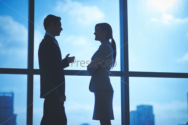 Outlines of business partners talking by the window in office