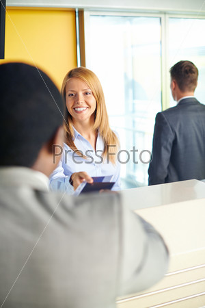 Smiling female returning documents to Afro-American businessman at the airport