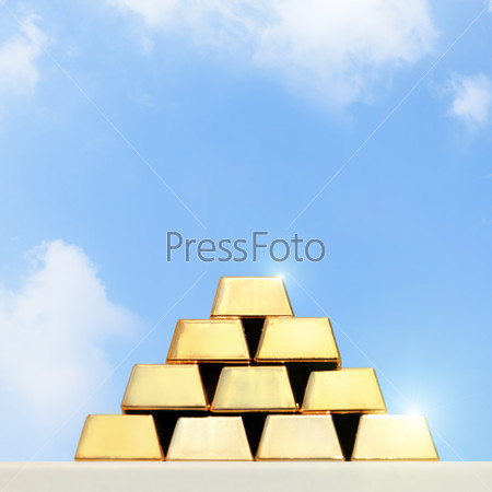 stacks and rows of gold ingots or golden bullion bars with sky background