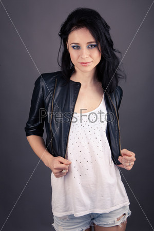 pretty girl in leather jacket with piercings on a gray background