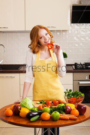 Smiling young woman in the kitchen with vegetables