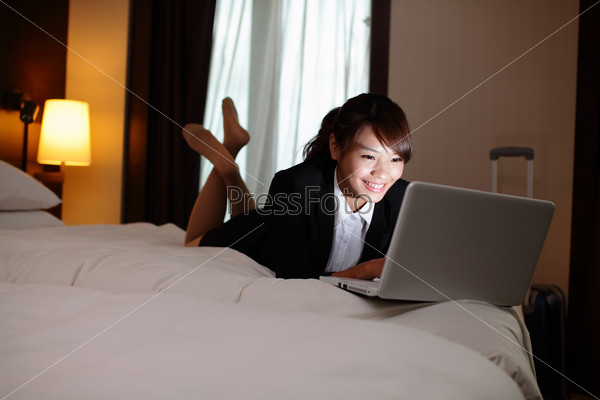 business woman working on bed with laptop in hotel at night. asian