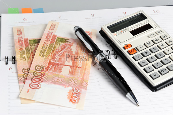 Weekly, black pen, calculator and money closeup