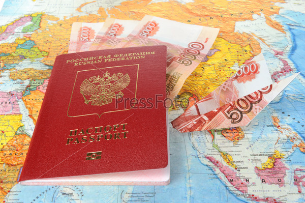 Russian international passport with money within and origami plane made from money on the world map