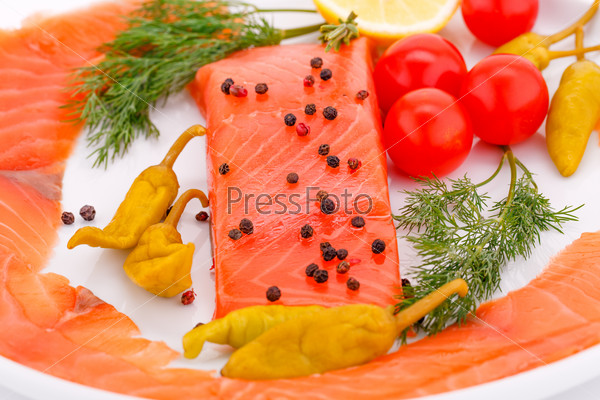 Salmon fillet with lemon, dill, pepper on plate.