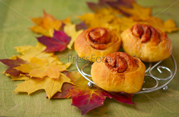 sweet pumpkin rolls cinnamon on a background of autumn leaves