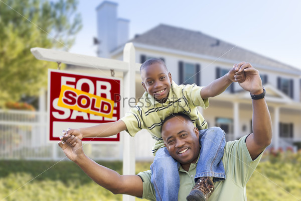 Happy African American Father and Son in Front of Home and Sold For Sale Real Estate Sign.