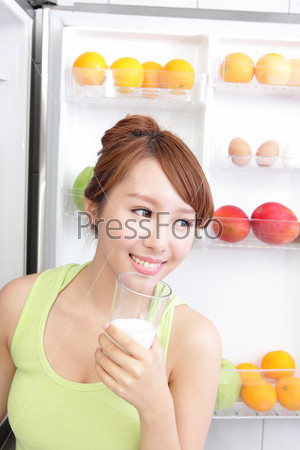 Healthy Eating Concept .Diet. Beautiful Young Woman drink\
milk near the Refrigerator. Fruits and Vegetables, asian\
model