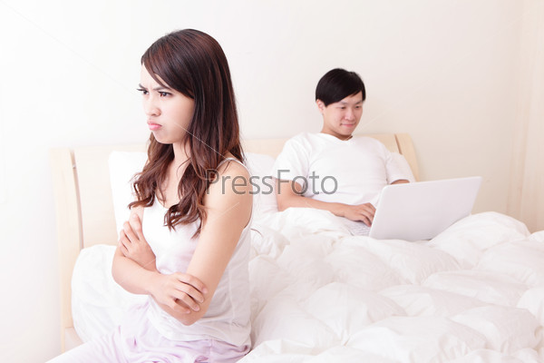 Couple with computer in bed.  woman upset and angry, Man happy using laptop. Asian people
