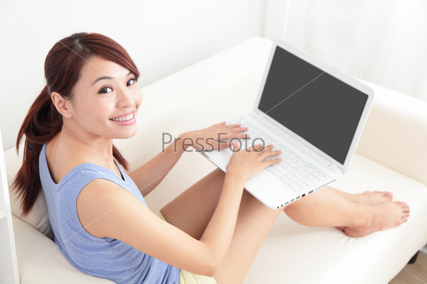 woman using laptop on sofa in the living room, empty computer screen is great for your copy space design, asian beauty