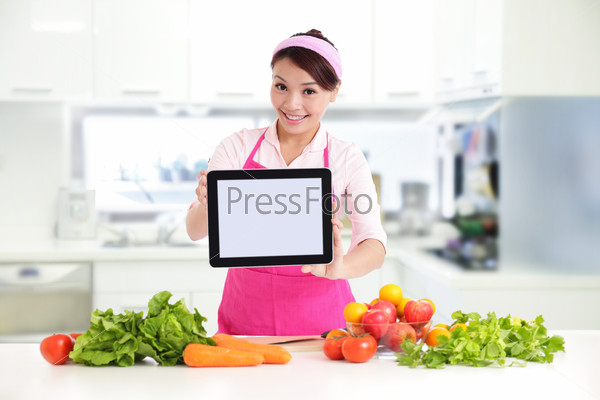 Happy smiling woman in kitchen holding tablet pc computer with health food, asian