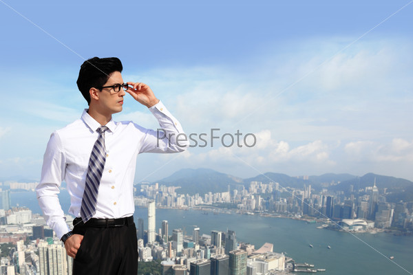 Successful handsome business man purposefully looking away with blue sky in the city