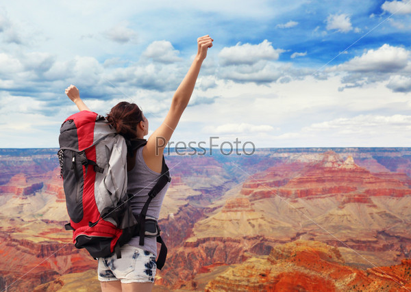 happy woman with backpack raised arm hands and looking to sky in grand canyon. asian