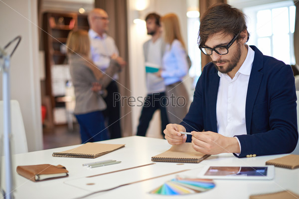 Thoughtful businessman with pen looking at empty notebook page at workplace