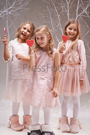 Group of ecstatic girls with candy hearts having fun in fairy garden