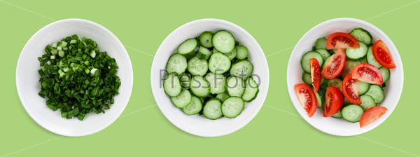 Fresh tomatoes, cucumbers and green onions chopped salad on a green background. Clipping path.