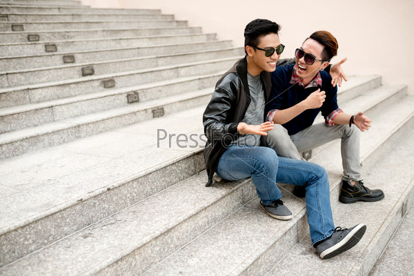 Best friends in sunglasses sitting on the steps and laughing