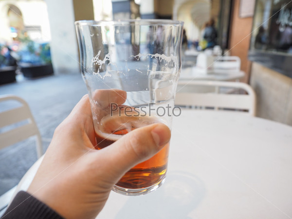 Hand holding a pint of British ale on a pub table - selective focus on beer over blurred background