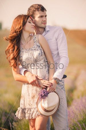 Happy marriage concept. Portrait of a beautiful kissing couple of hipsters in trendy clothing. Outdoor shot. Happy couple having great time together - photographed at sunset against sun
